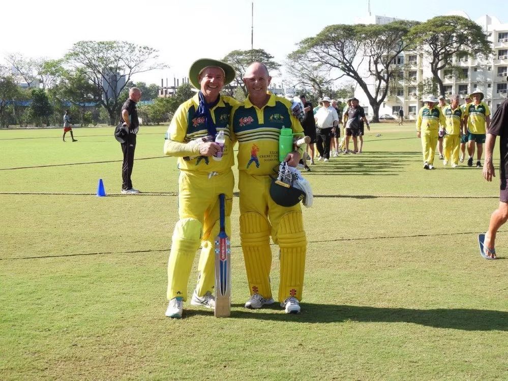 Two men in yellow cricket uniforms, one with a bat