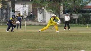 Batter in yellow swings bat in an ongoing Cricket match