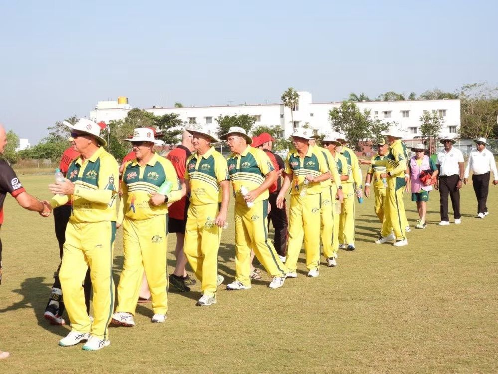 Cricket players in yellow uniforms and hats walking on a field