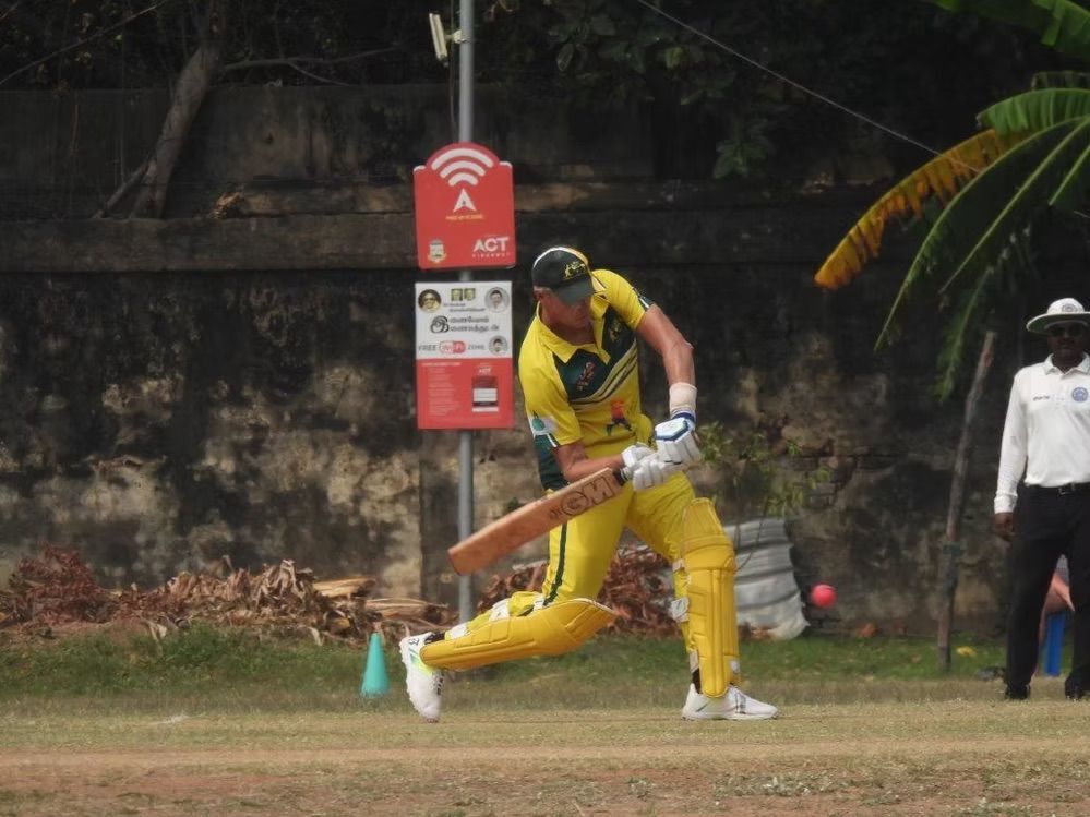 Cricket player in yellow uniform batting on a field