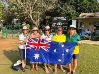Five people in sports attire holding an Australian flag