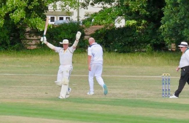 Cricketer in white raises arms celebrating a score