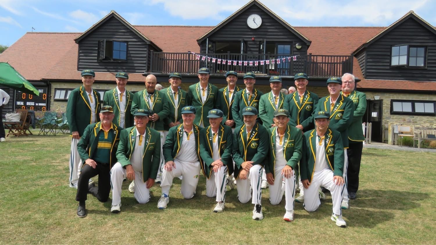 Group of men in green jackets, posing on grass