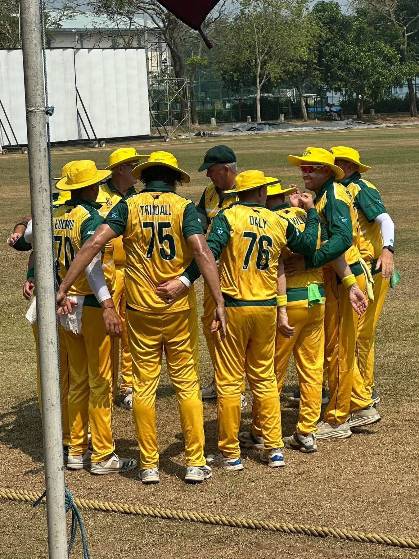 Australian cricket team in yellow and green uniforms huddling