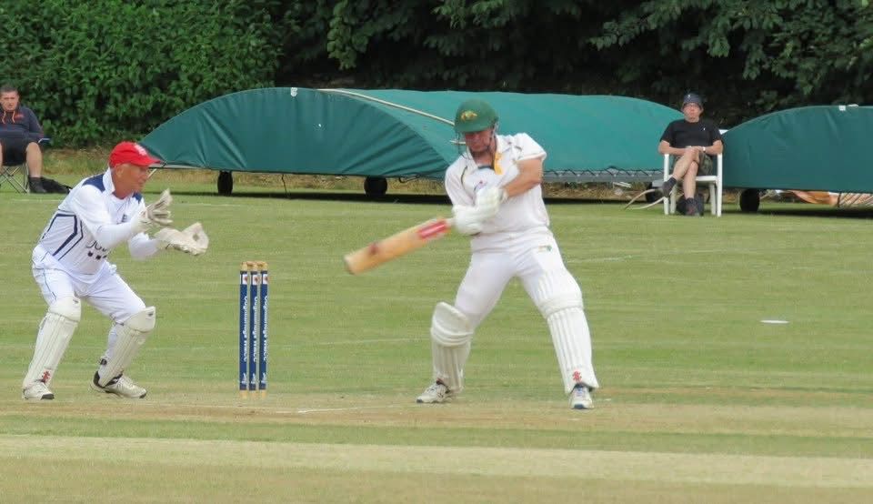 Cricket batsman in white uniform swings bat