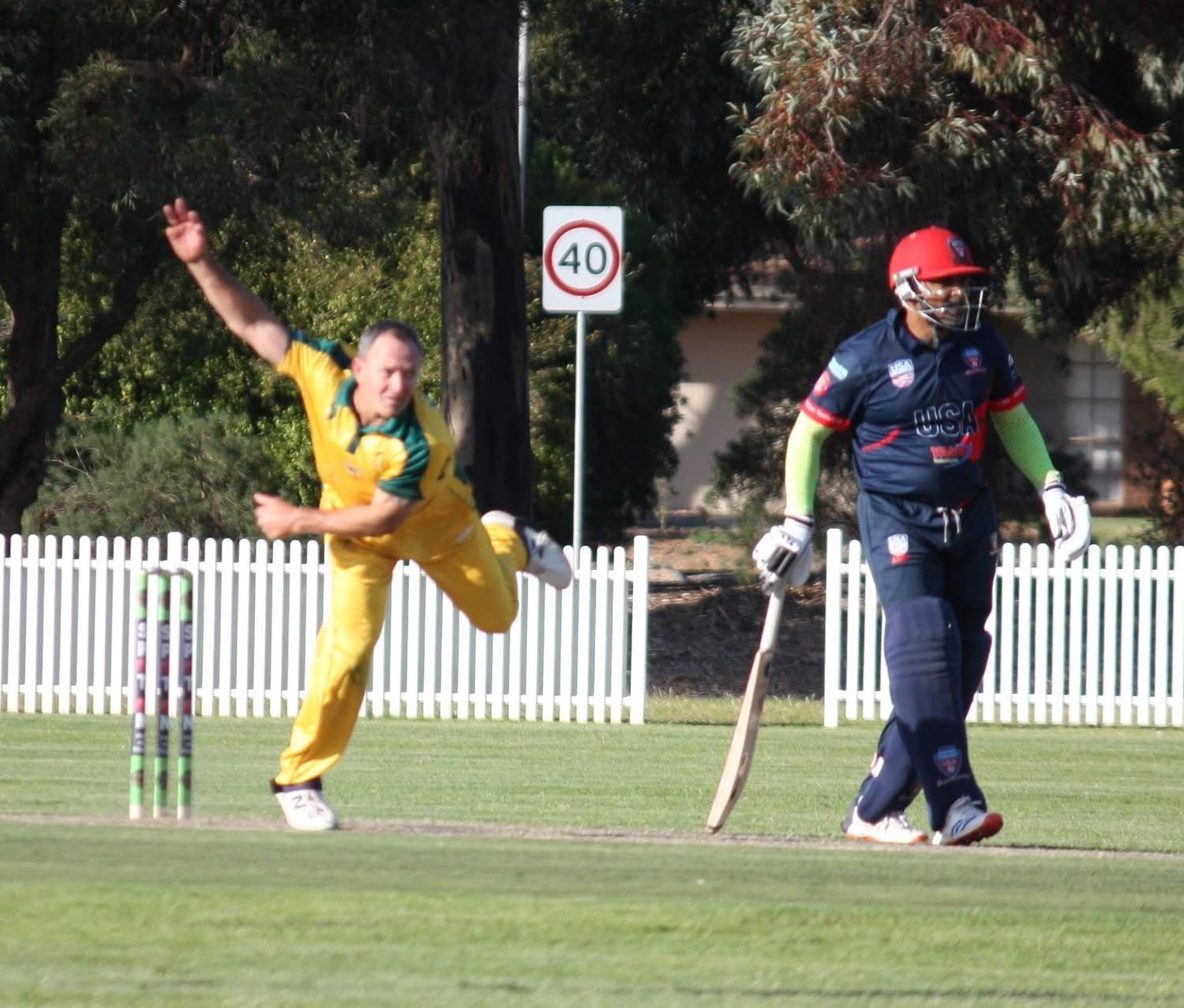 Cricketer in yellow bowls on a grassy field