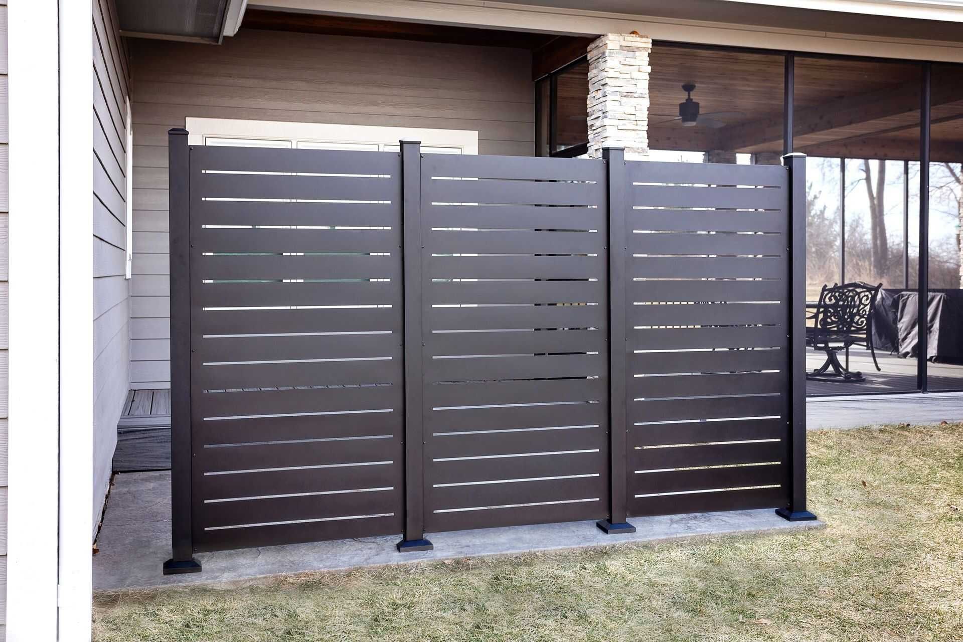 Black aluminum privacy panels with horizontal slots beside a pool equipment area