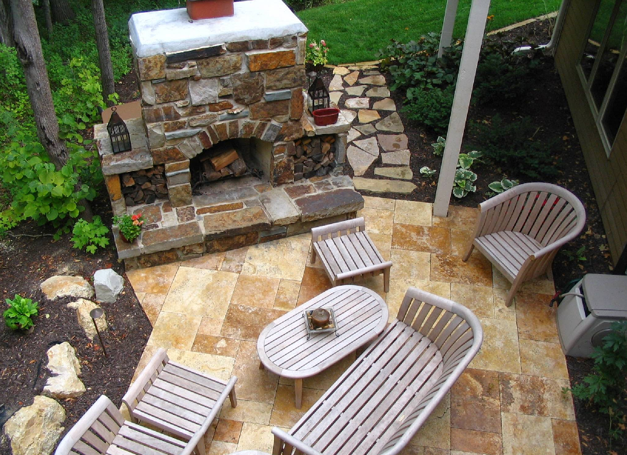 Outdoor patio with stone fireplace, wood furniture, and stone pathway.