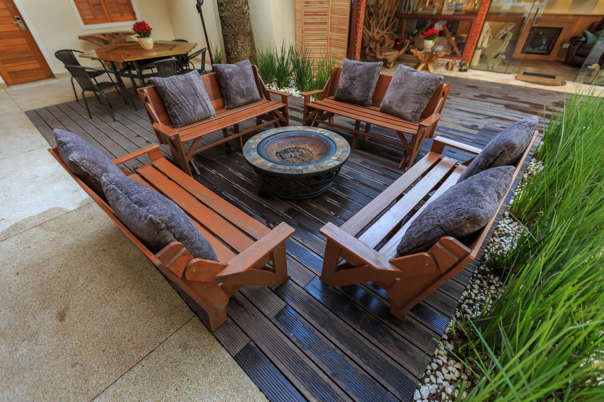 Outdoor patio seating area with wooden chairs around a fire pit on a deck