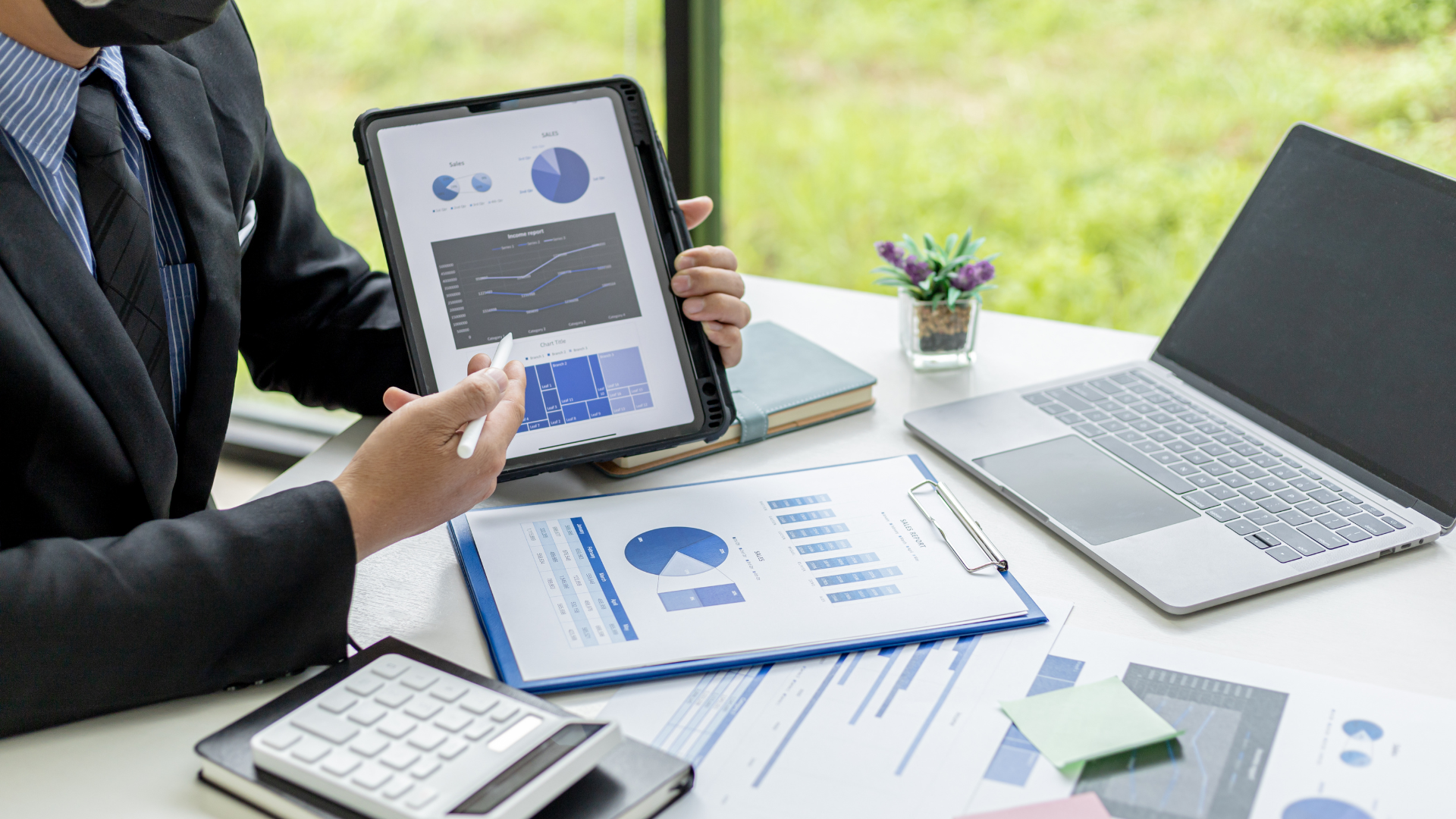 a man wearing a mask is looking at a tablet with graphs on it
