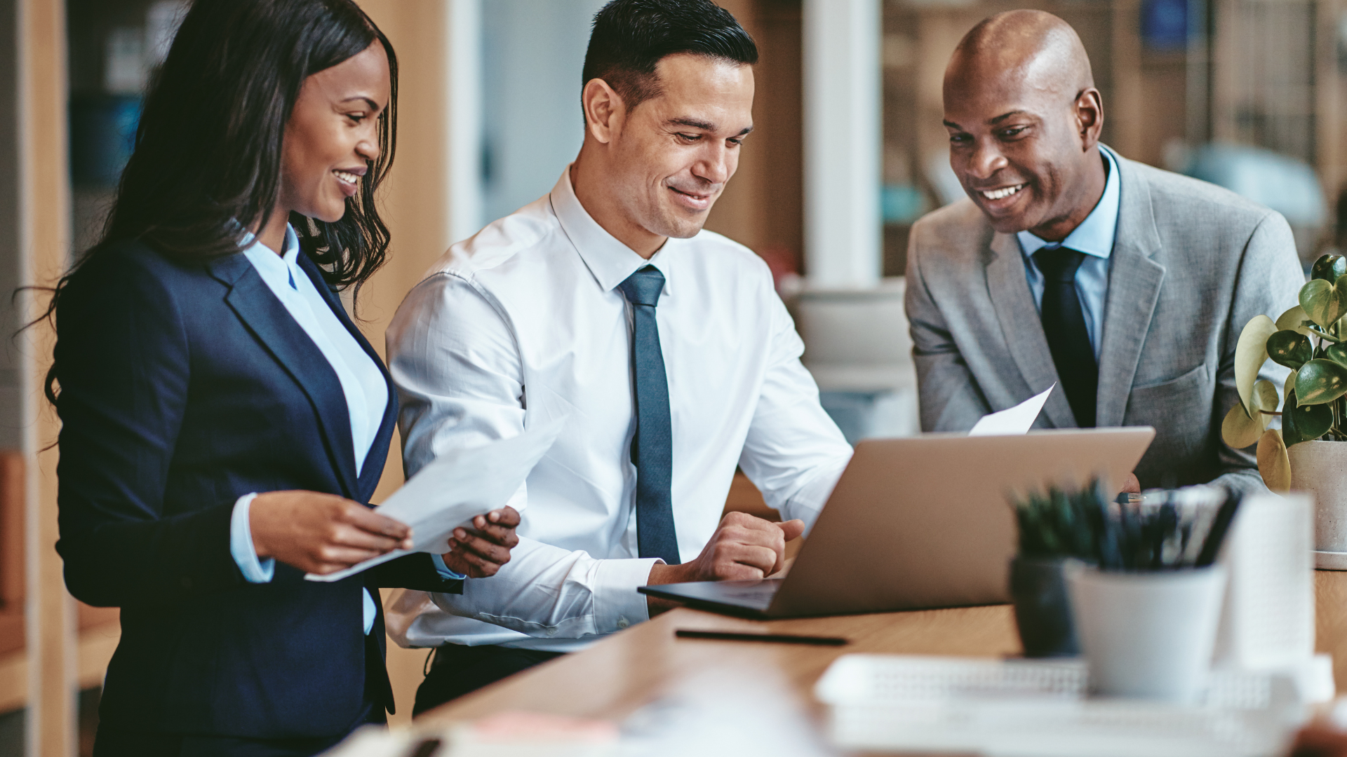 A group of business people are looking at a laptop computer.