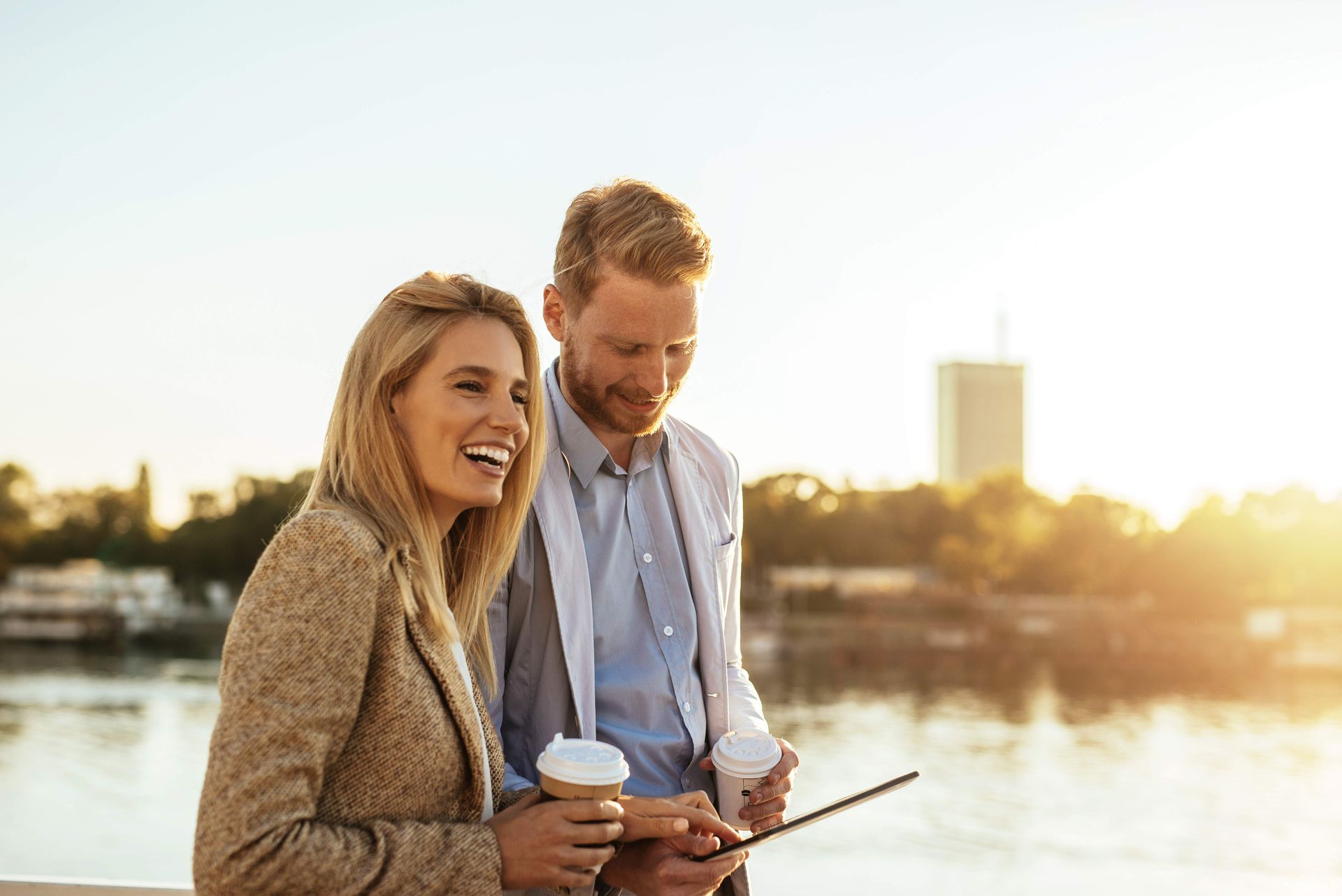 A man and a woman are standing next to each other looking at a tablet.