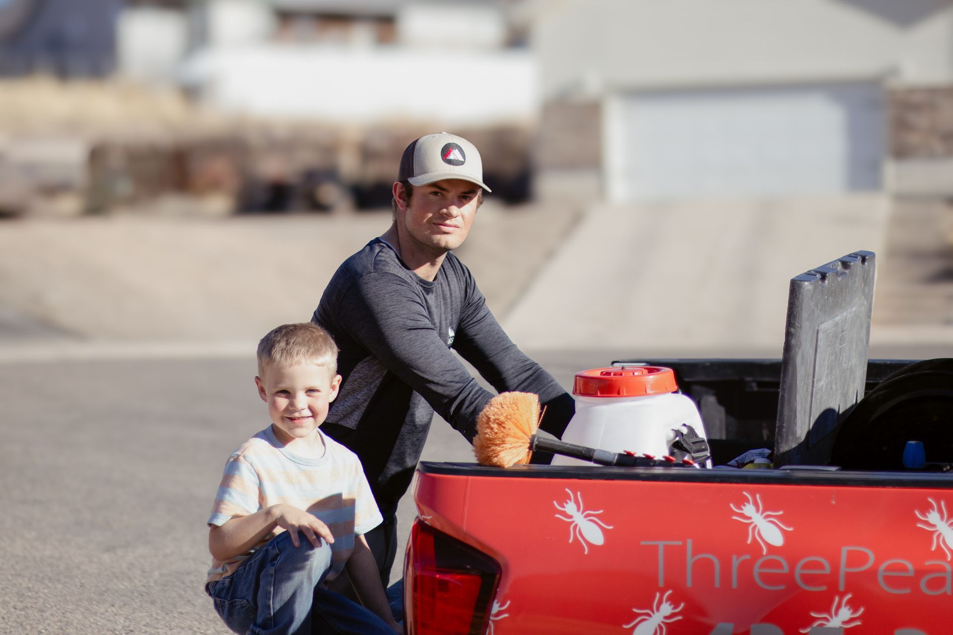 A Three Peaks Pest Control technician showing a boy his equipment at a home Brian Head, Utah.
