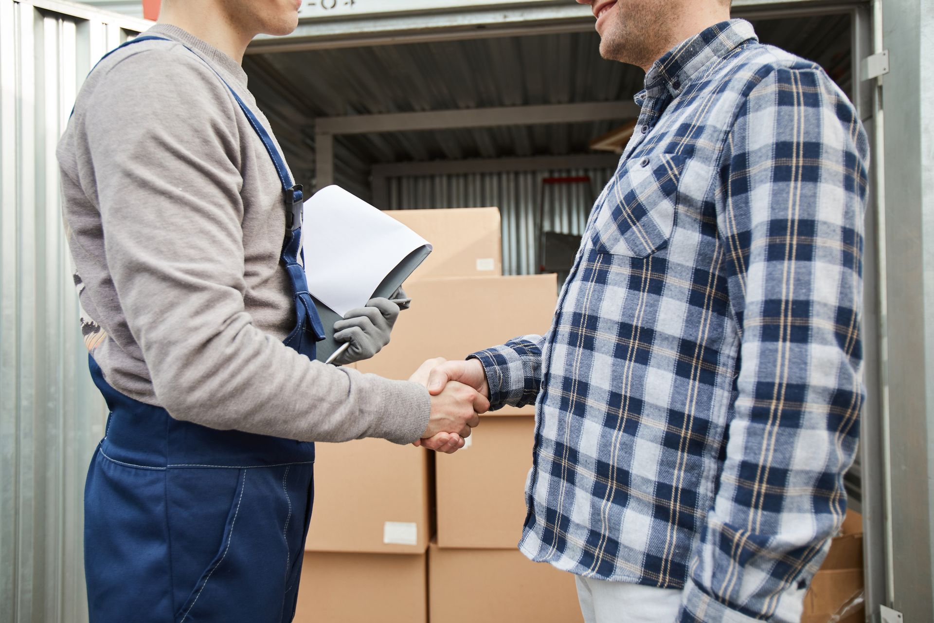 Two men are shaking hands in front of a warehouse.