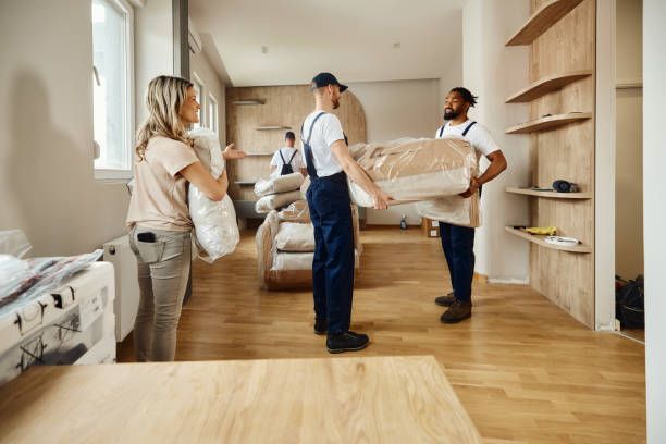 Woman guiding movers who are carrying new furniture at her apartment