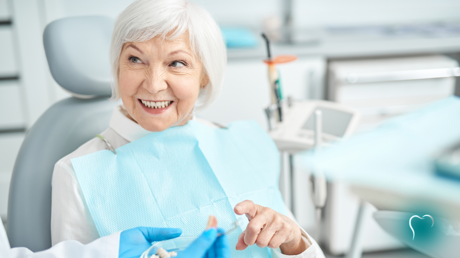 Smiling dental patient holding a blue bib in a bright dentist office