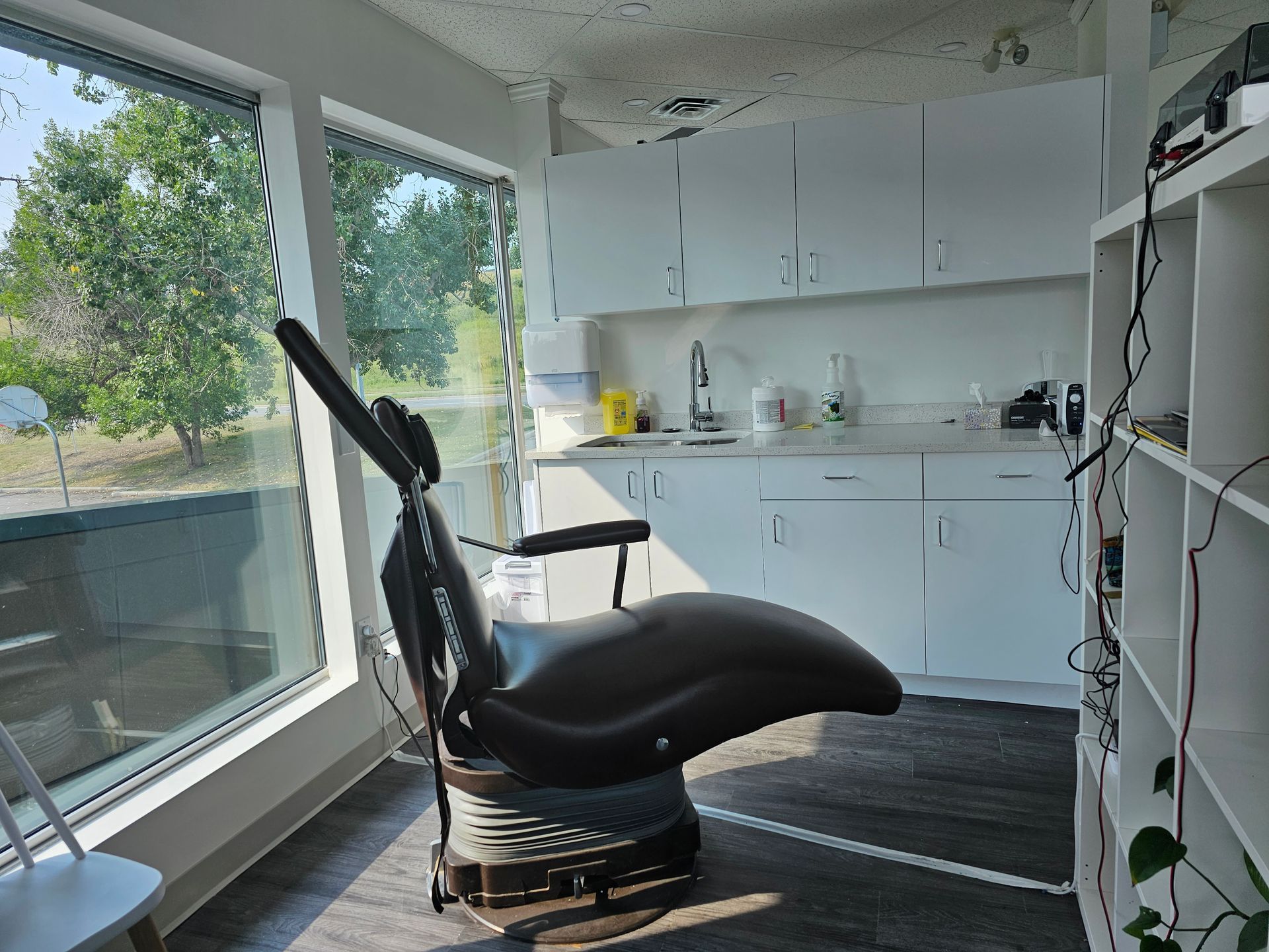 Black massage chair in a bright kitchenette with large windows and cabinets