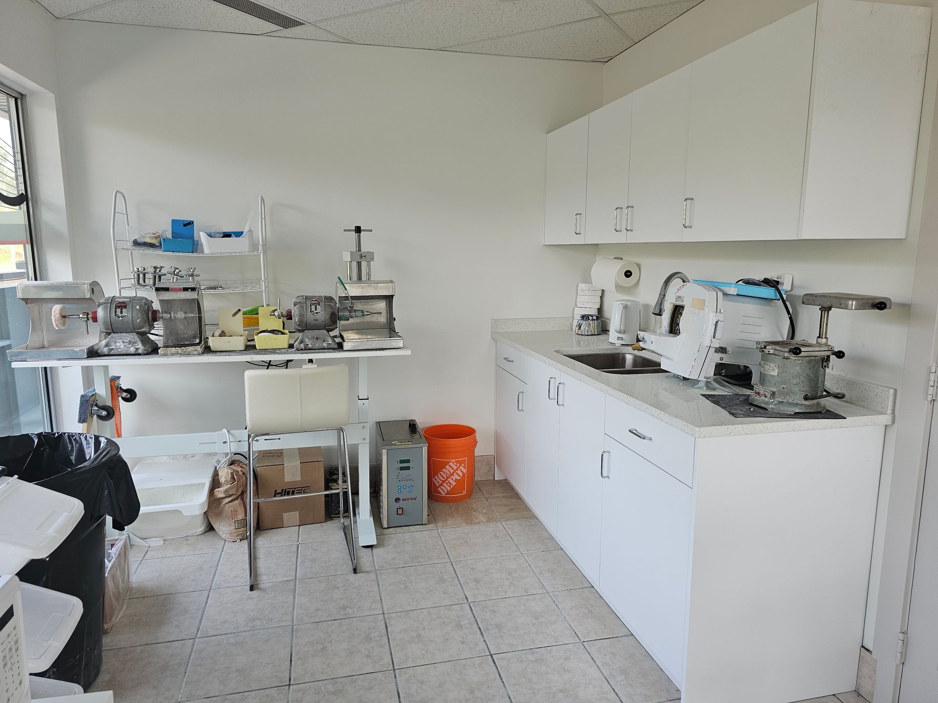 Bright clinical lab with counters, cabinets, and scientific equipment on white tile floor.