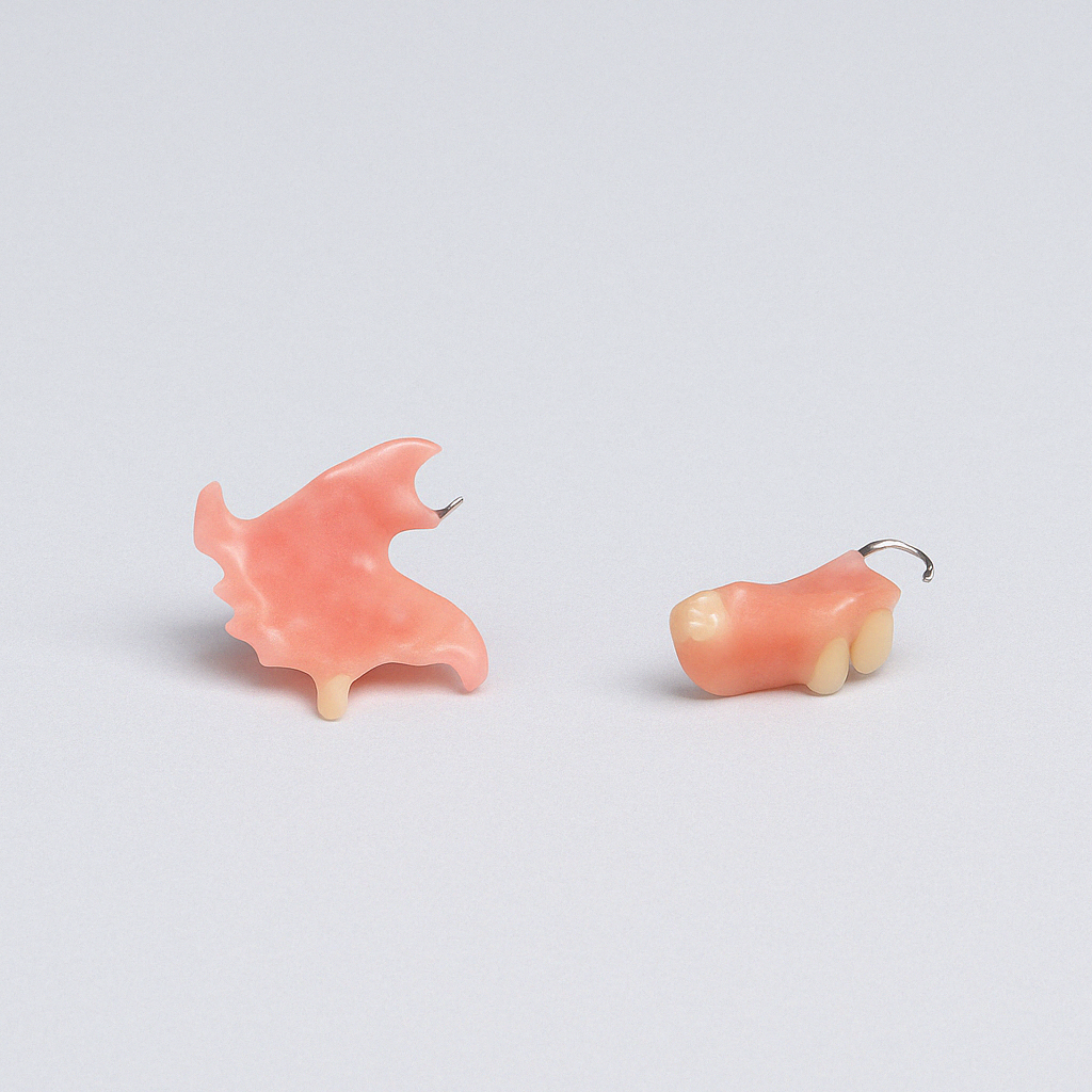 Two small peach-colored toy figurines on a light gray surface
