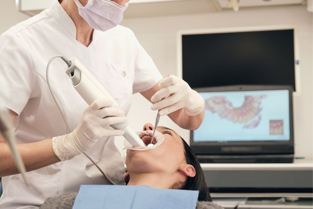 Dentist pointing at teeth on a screen during a consultation in an office.