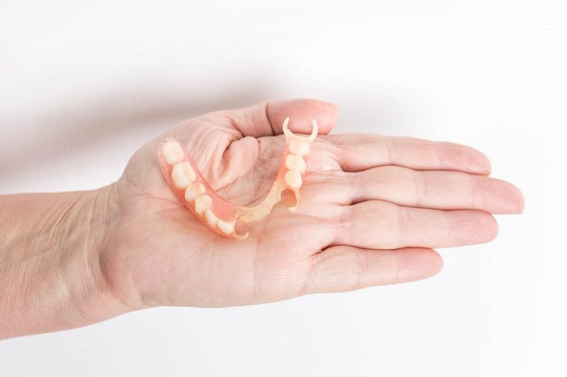 Dentist pointing at teeth on a screen during a consultation in an office.