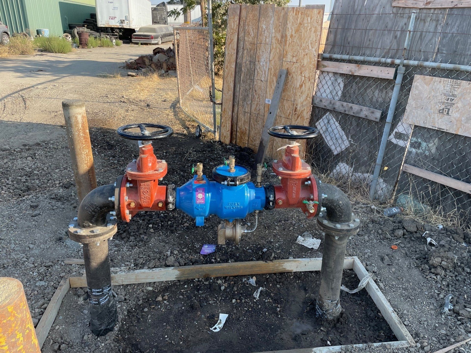 A bunch of pipes and valves are sitting in the dirt.