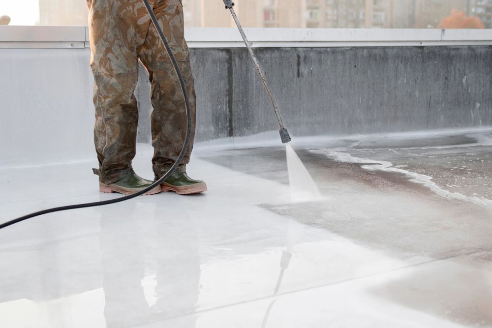 A Man is Using a High Pressure Washer to Clean a Roof — Derek's Dirty Deeds In Burrum Heads, QLD