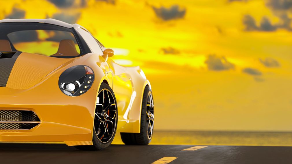 Auto sportiva gialla su strada, con sfondo al tramonto.