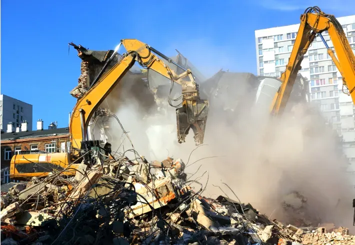 Two bulldozers are demolishing a building in a city.