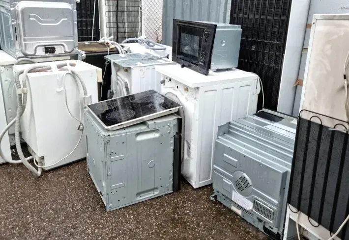A bunch of old appliances are stacked on top of each other on the ground.