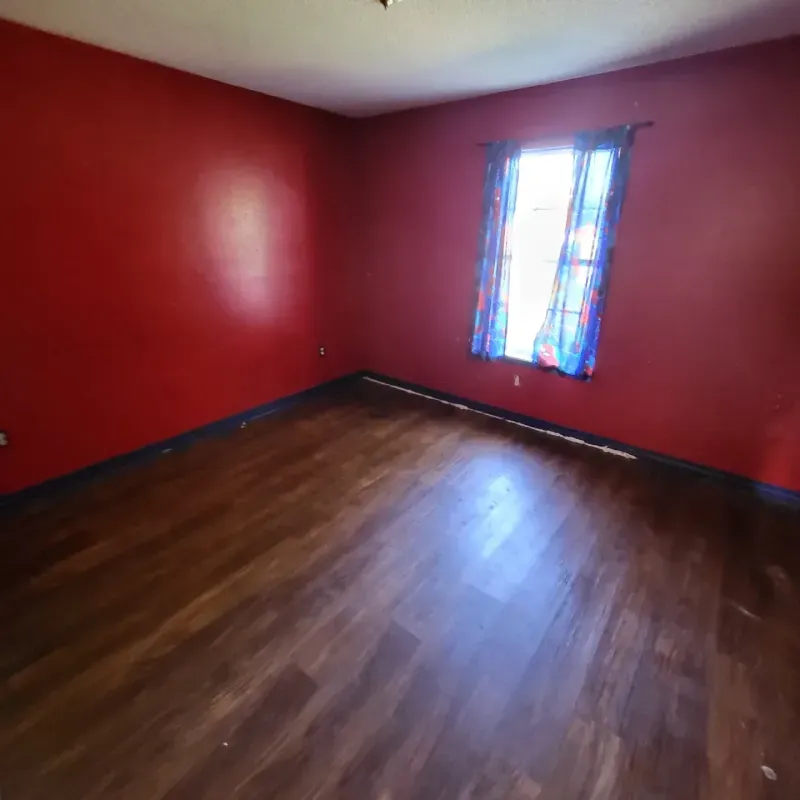 An empty room with red walls and a window