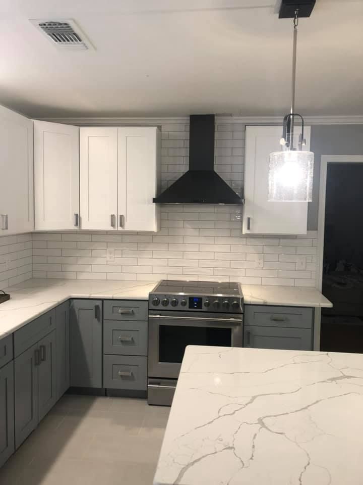 A kitchen with white cabinets , a stove , and a hood.