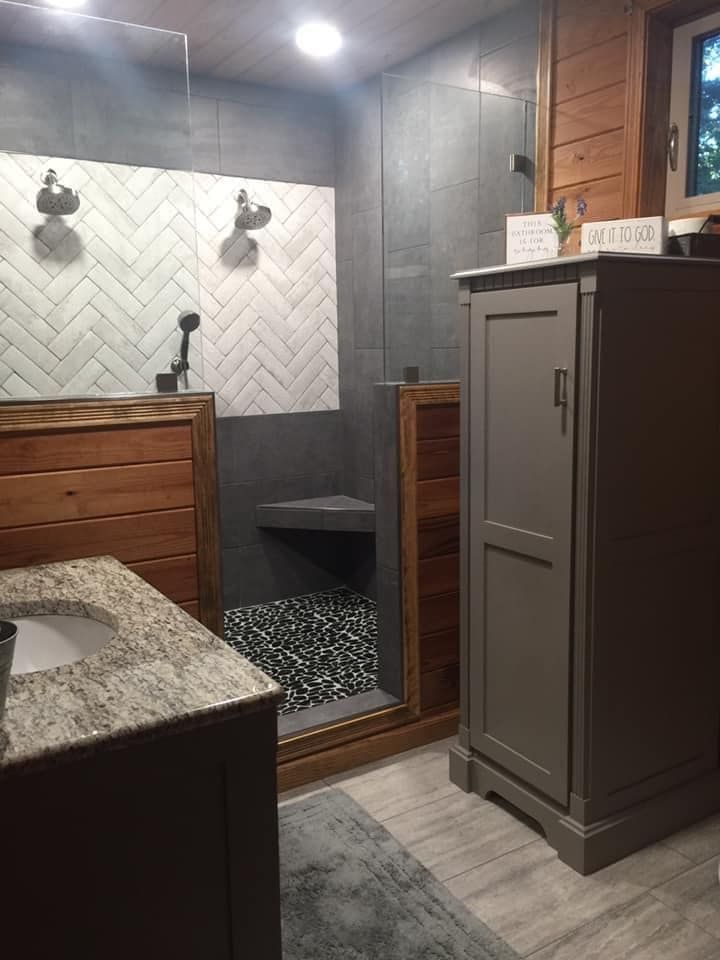A bathroom with a sink , cabinet , and walk in shower.