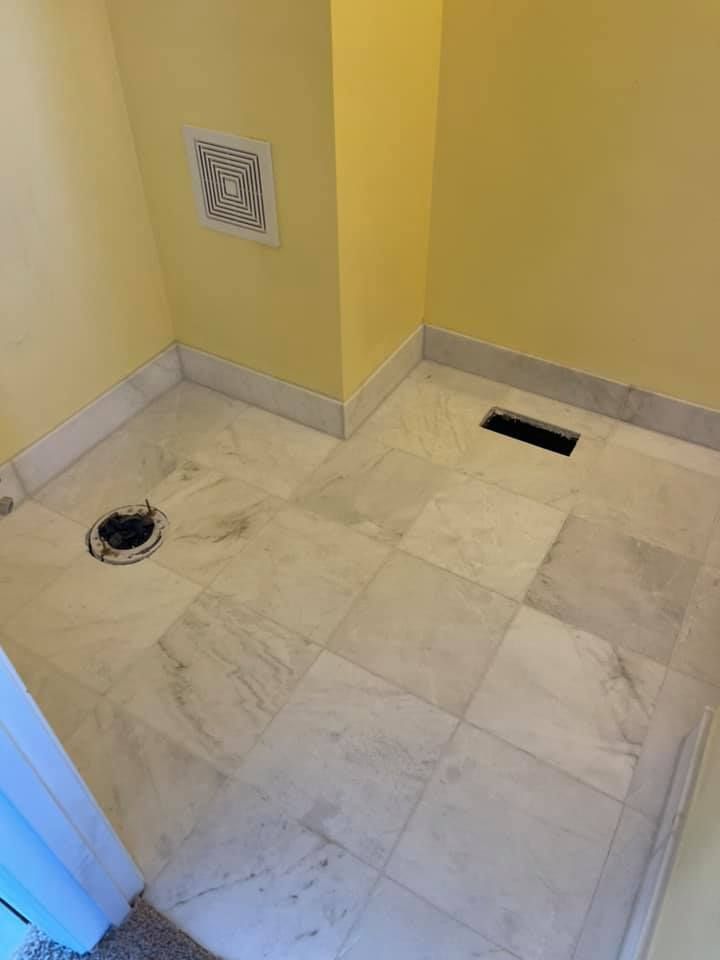 A bathroom with a marble floor and a fan on the wall.