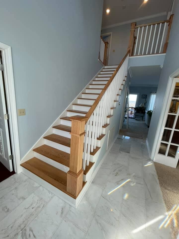 A staircase with wooden steps and white railings in a hallway in a house.