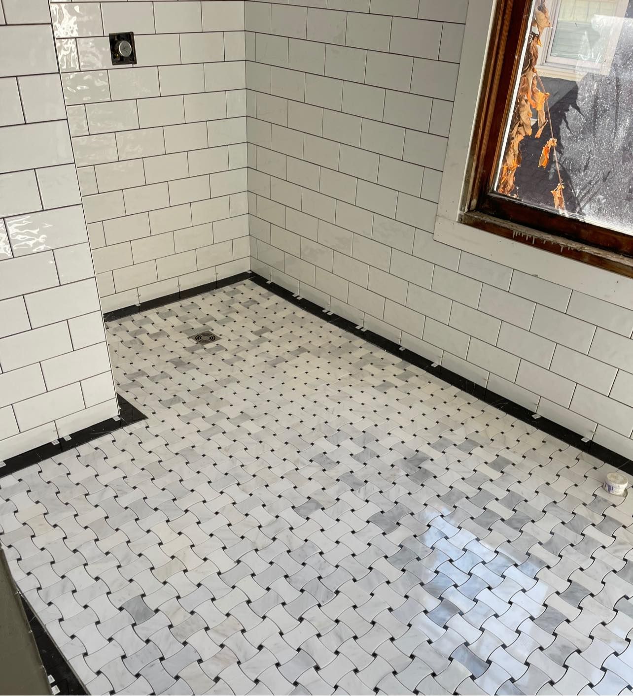 A bathroom with white tiles and a window