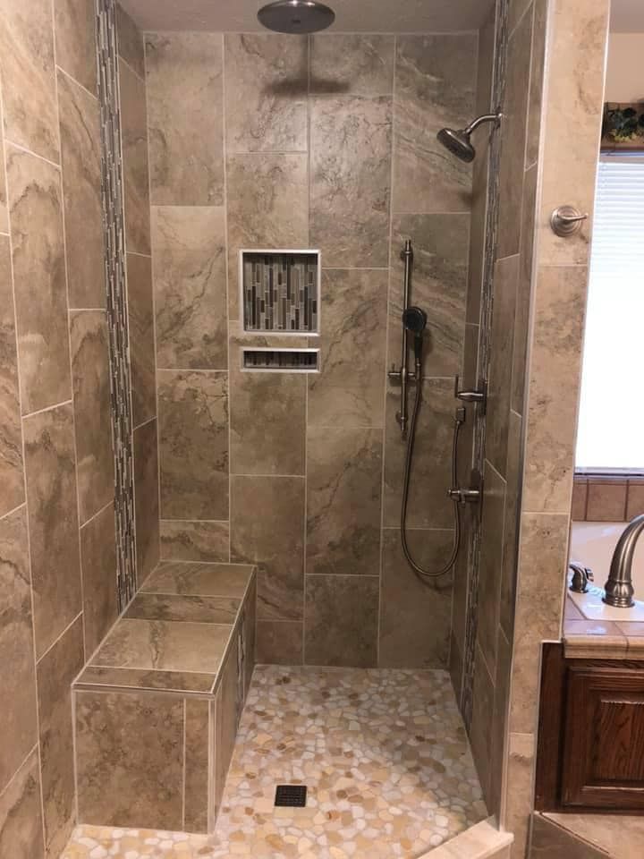 A walk in shower with a bench and a shower head in a bathroom.