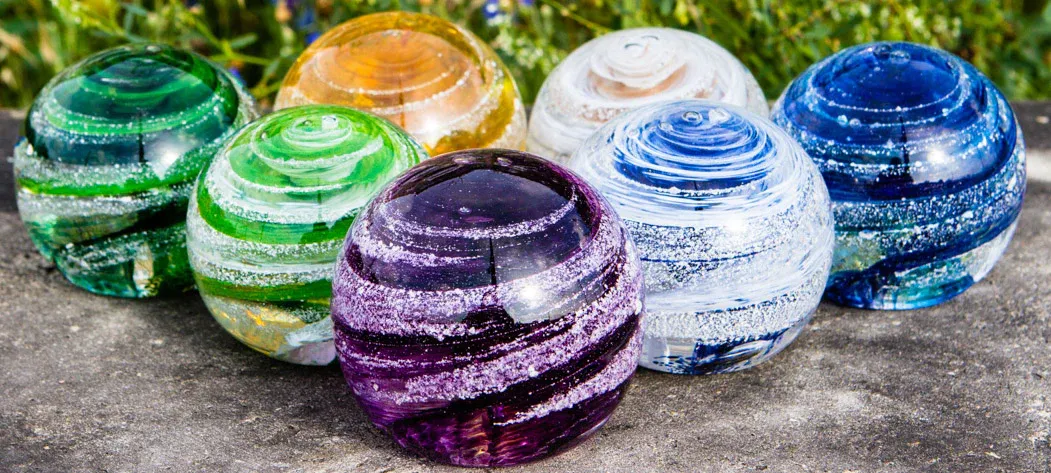 A group of colorful glass balls sitting on top of a concrete surface.