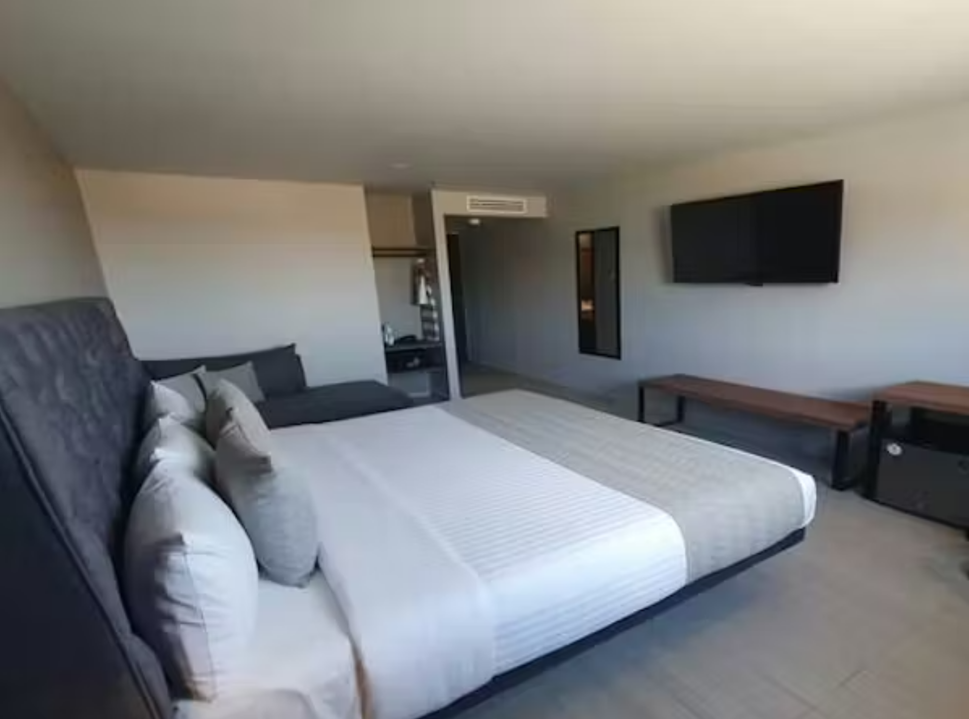 Habitación de hotel moderna con cama, sofá y TV.