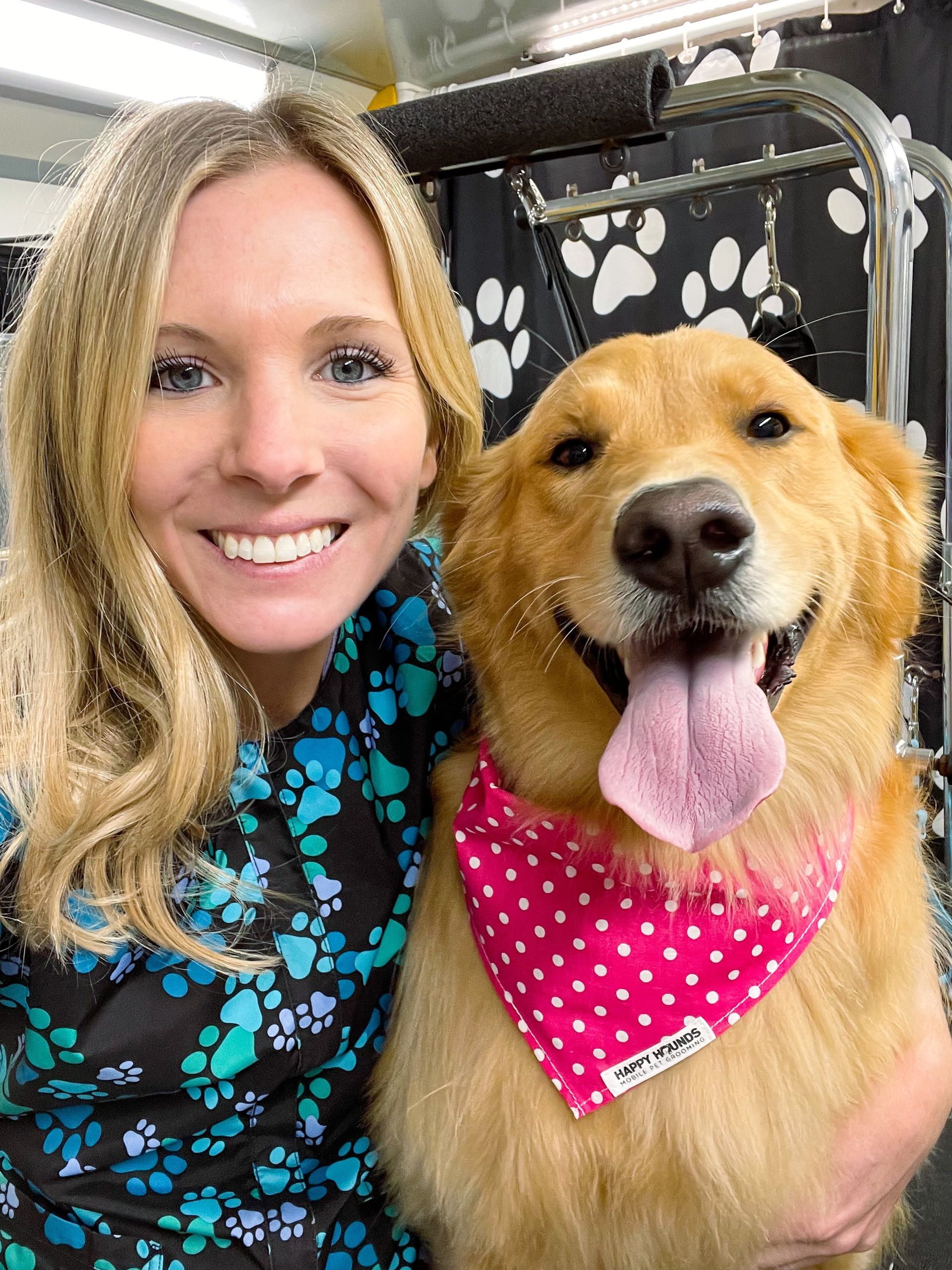 A woman is holding a dog wearing a pink bandana.