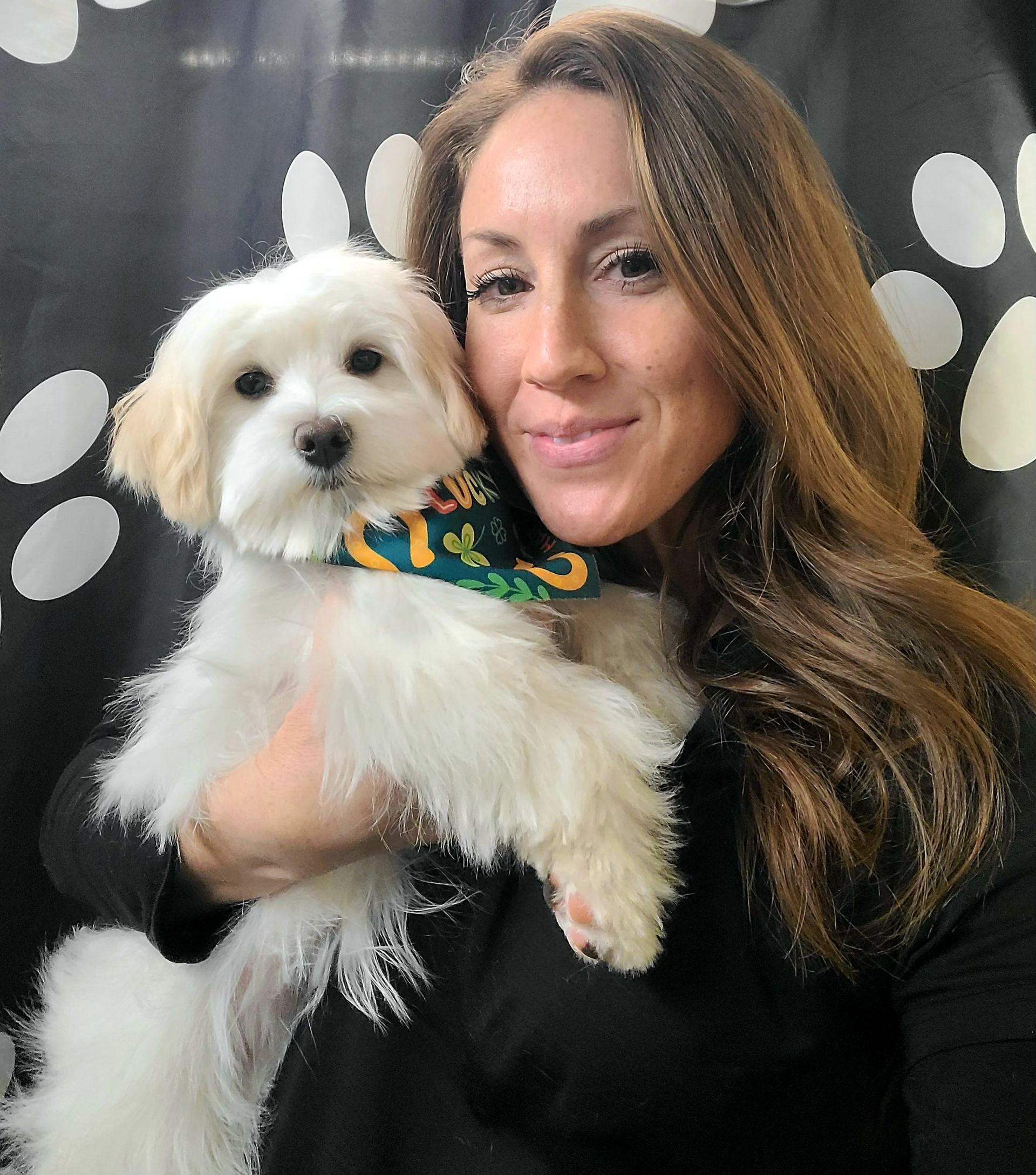 A woman is holding a small white dog in her arms.