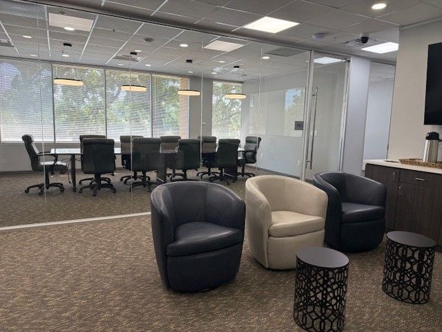 A large office with lots of windows and tables and chairs.