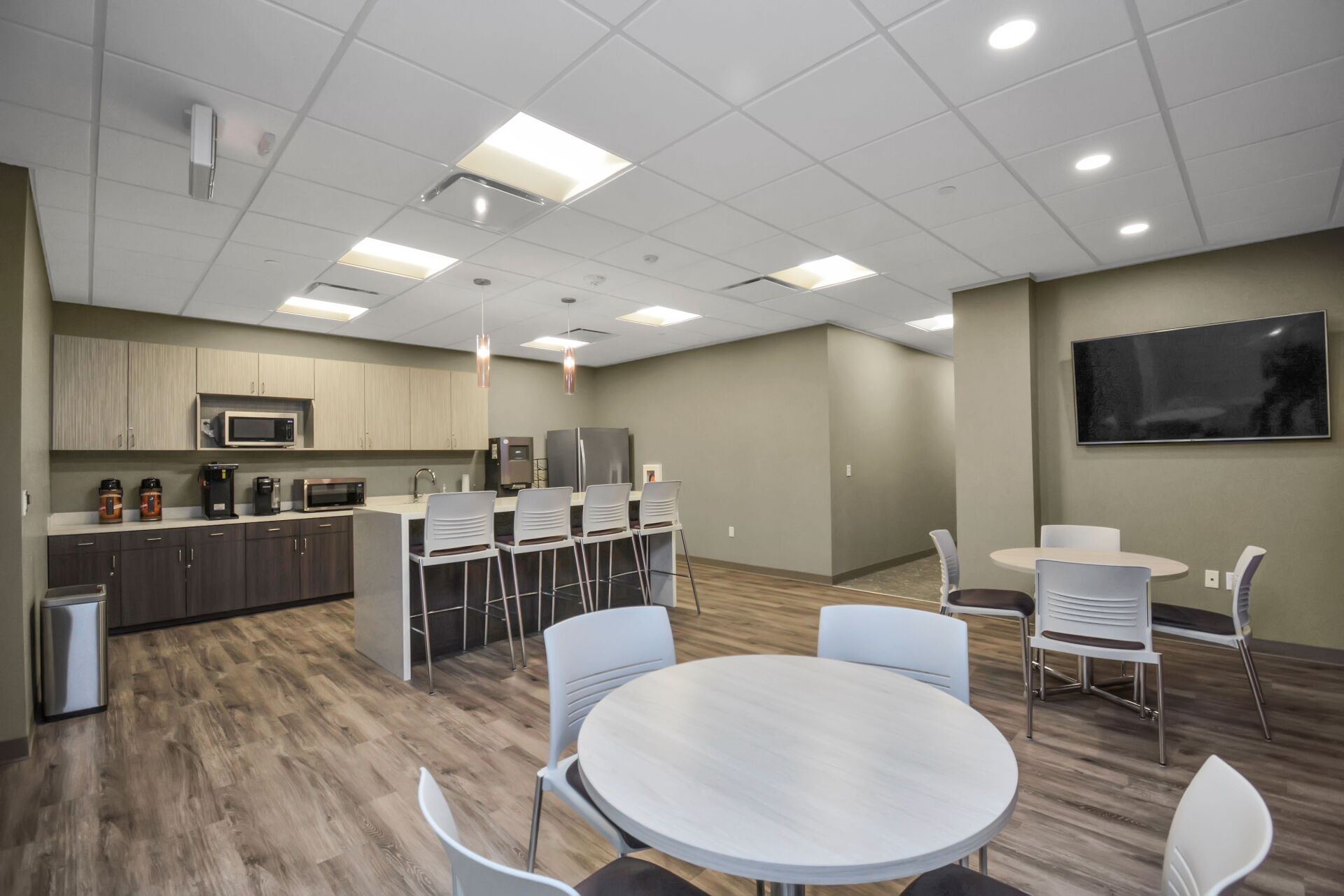 A kitchen with tables and chairs and a flat screen tv.