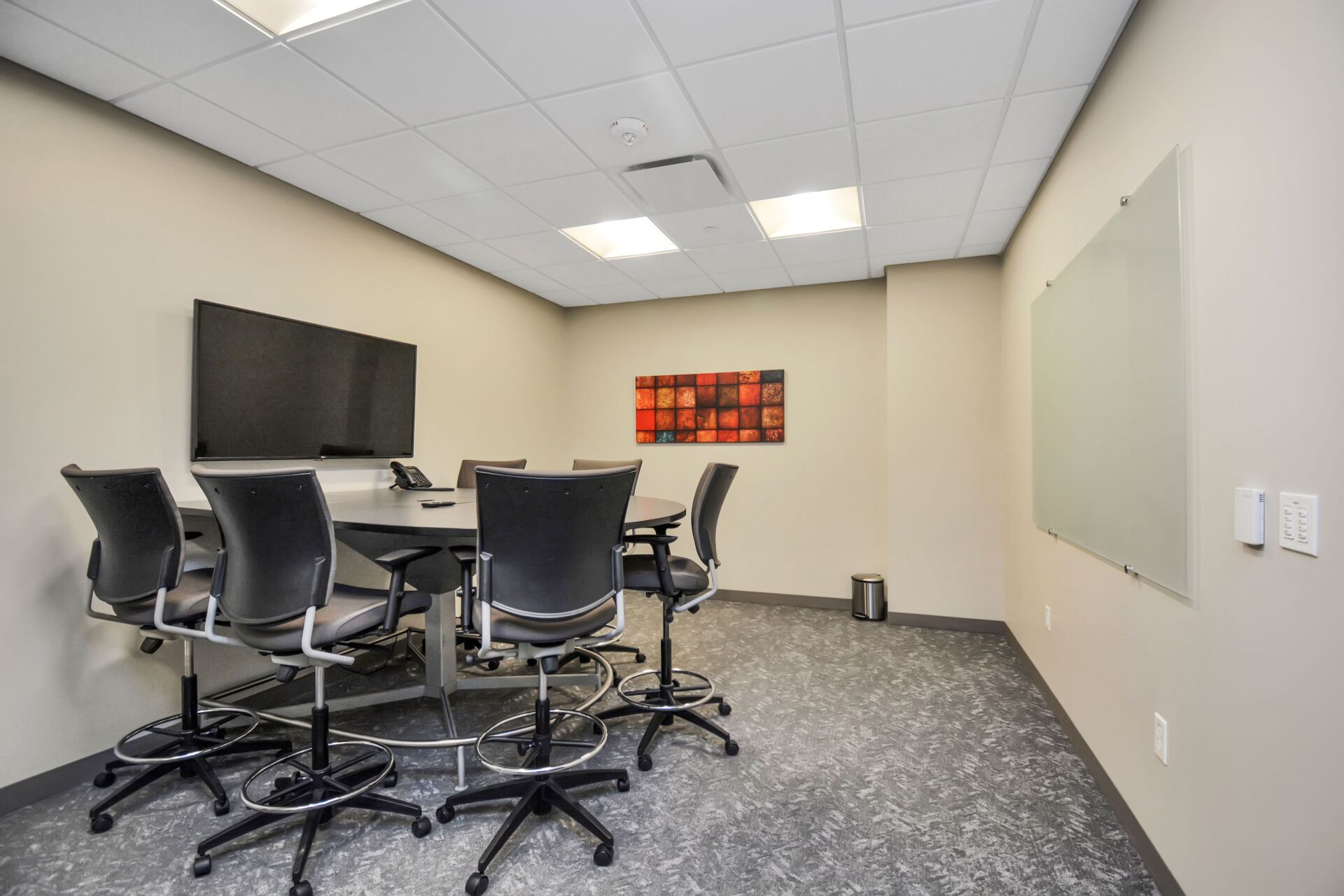A conference room with a table and chairs and a large flat screen tv.