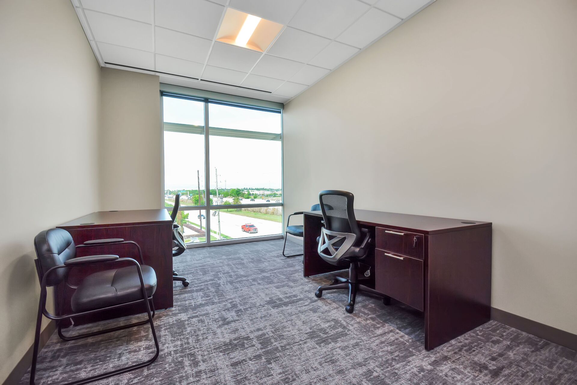 A small office with two desks and two chairs.