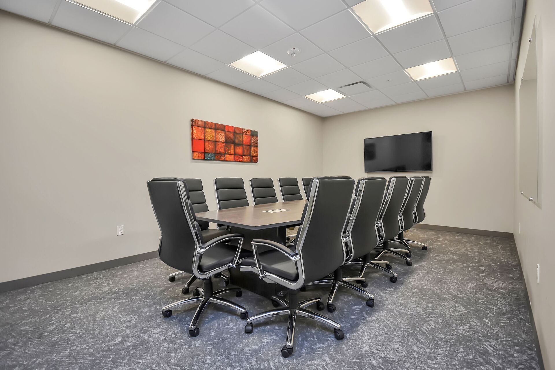 A conference room with a long table and chairs and a flat screen tv.