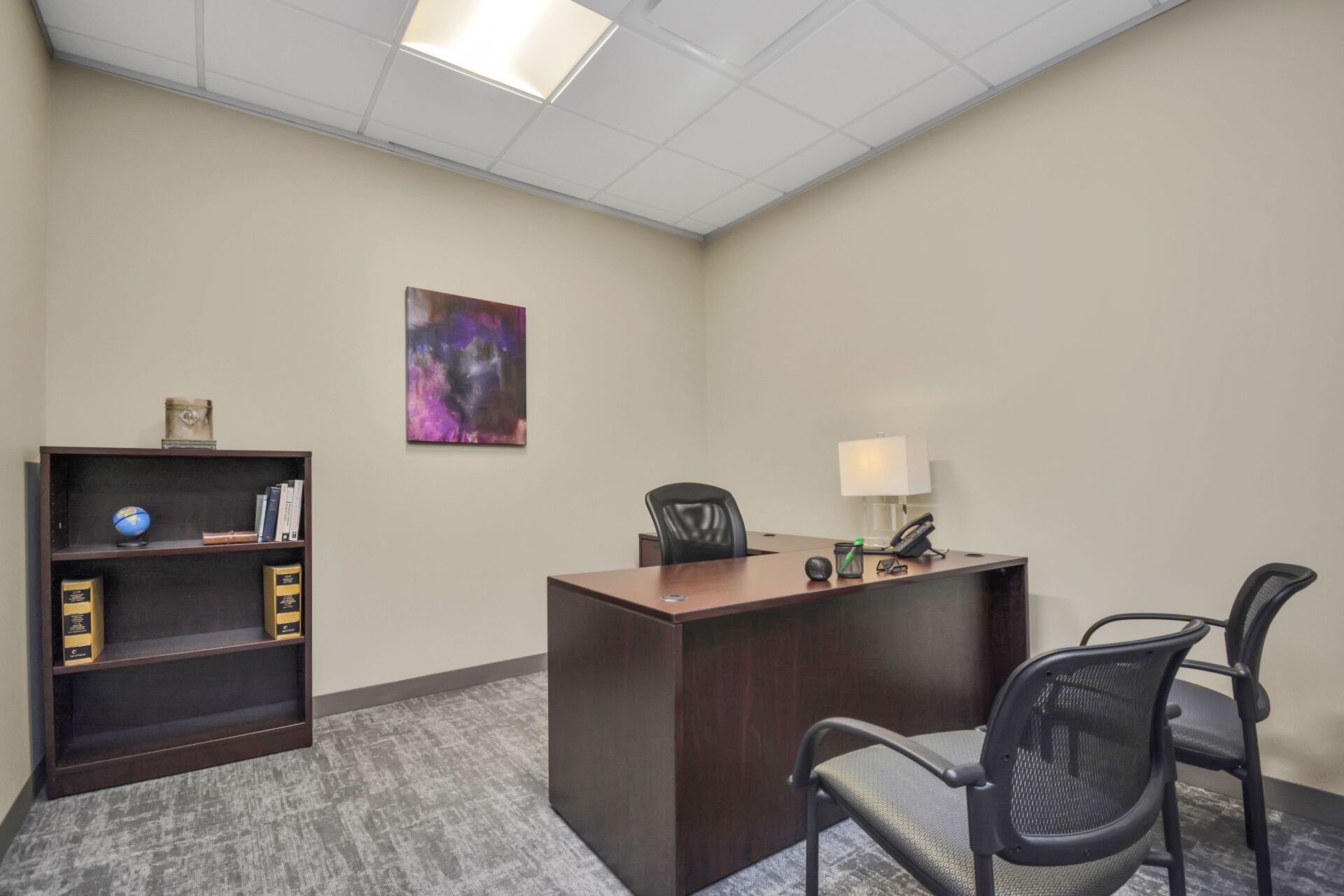 A small office with a desk and chairs in it.
