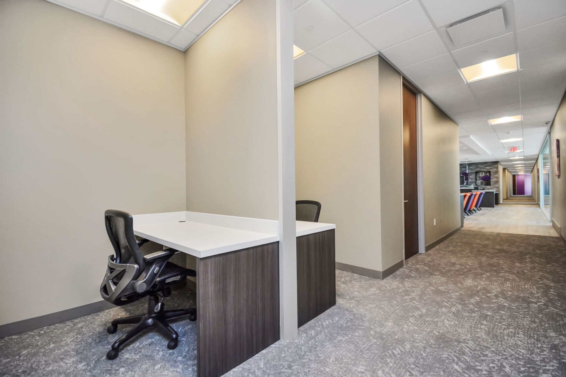 A small office with a desk and chair in a hallway.