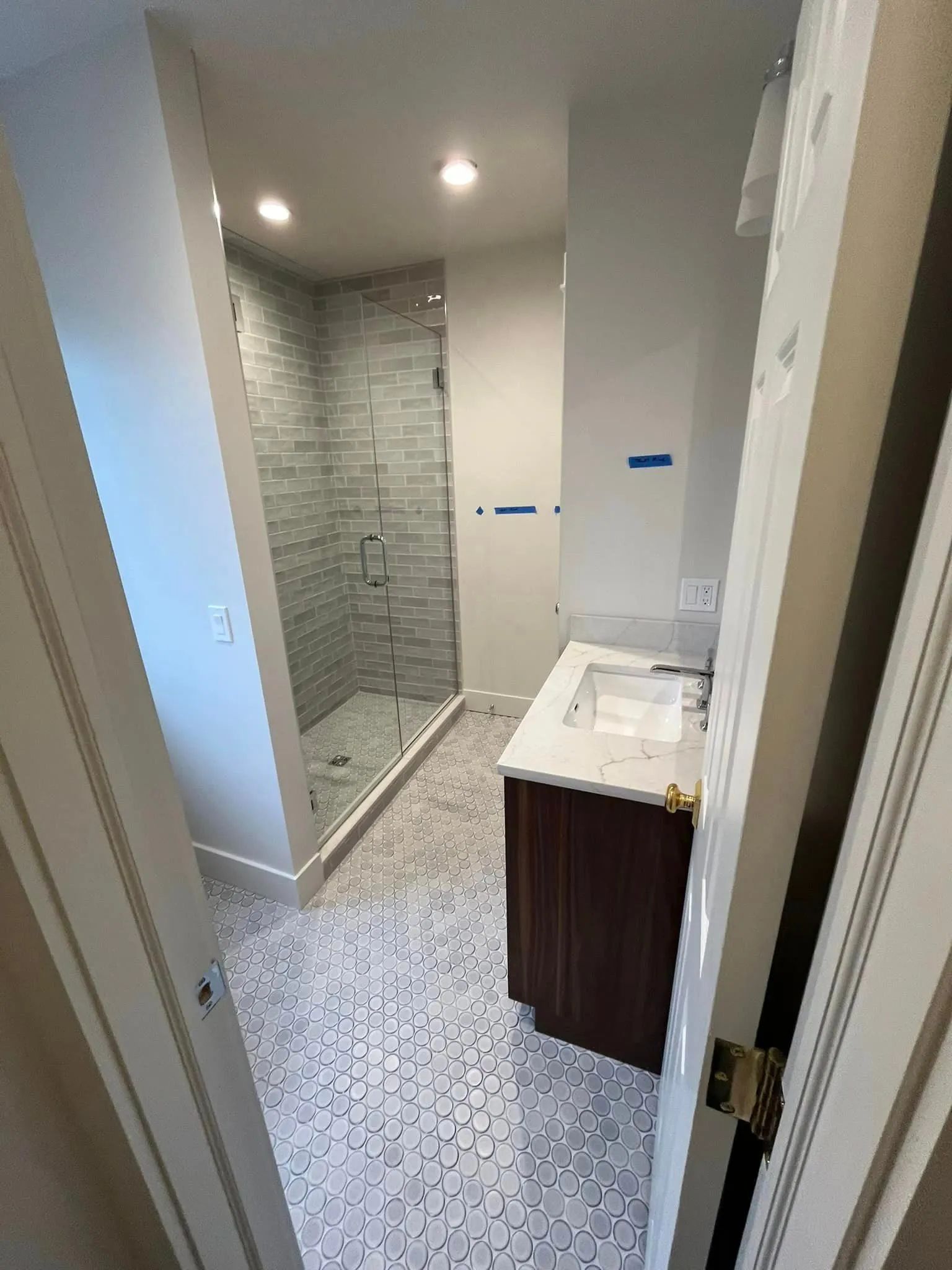 Modern bathroom with tiled shower, vanity, and recessed ceiling lights.