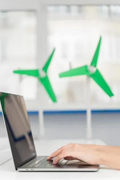 A person is typing on a laptop with two green airplanes in the background.